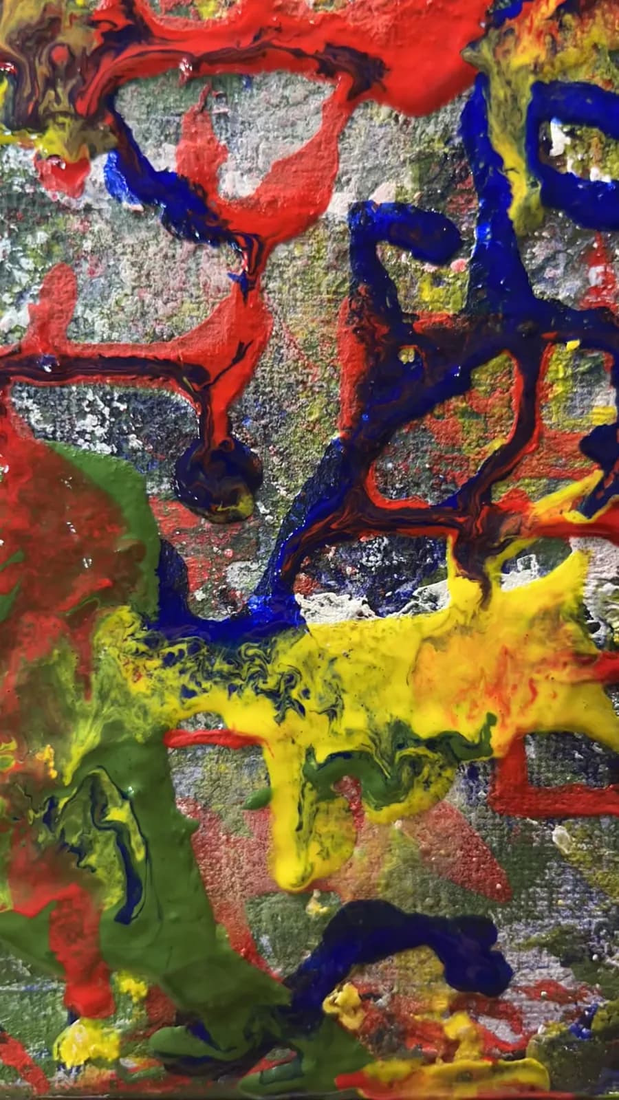 Close-up of wet natural pigment paint in red, blue, yellow and green on canvas